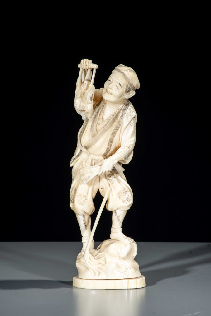 Marine ivory - Signed Gyokushi 玉之 - A marine ivory okimono of a man with a puppet. - Meiji period (19th century) #1.0