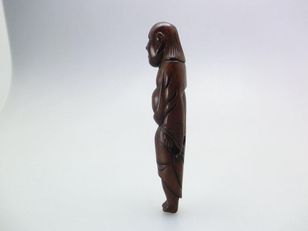 Ένα ψηλό Netsuke που απεικονίζει έναν όρθιο άνδρα με θυμωμένη έκφραση. - Ξύλο - Ιαπωνία - Edo Period (1600-1868) #1.0