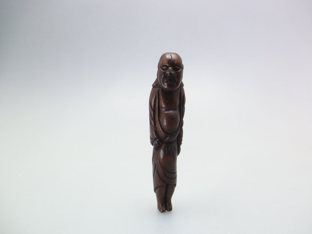 Ένα ψηλό Netsuke που απεικονίζει έναν όρθιο άνδρα με θυμωμένη έκφραση. - Ξύλο - Ιαπωνία - Edo Period (1600-1868) #1.0